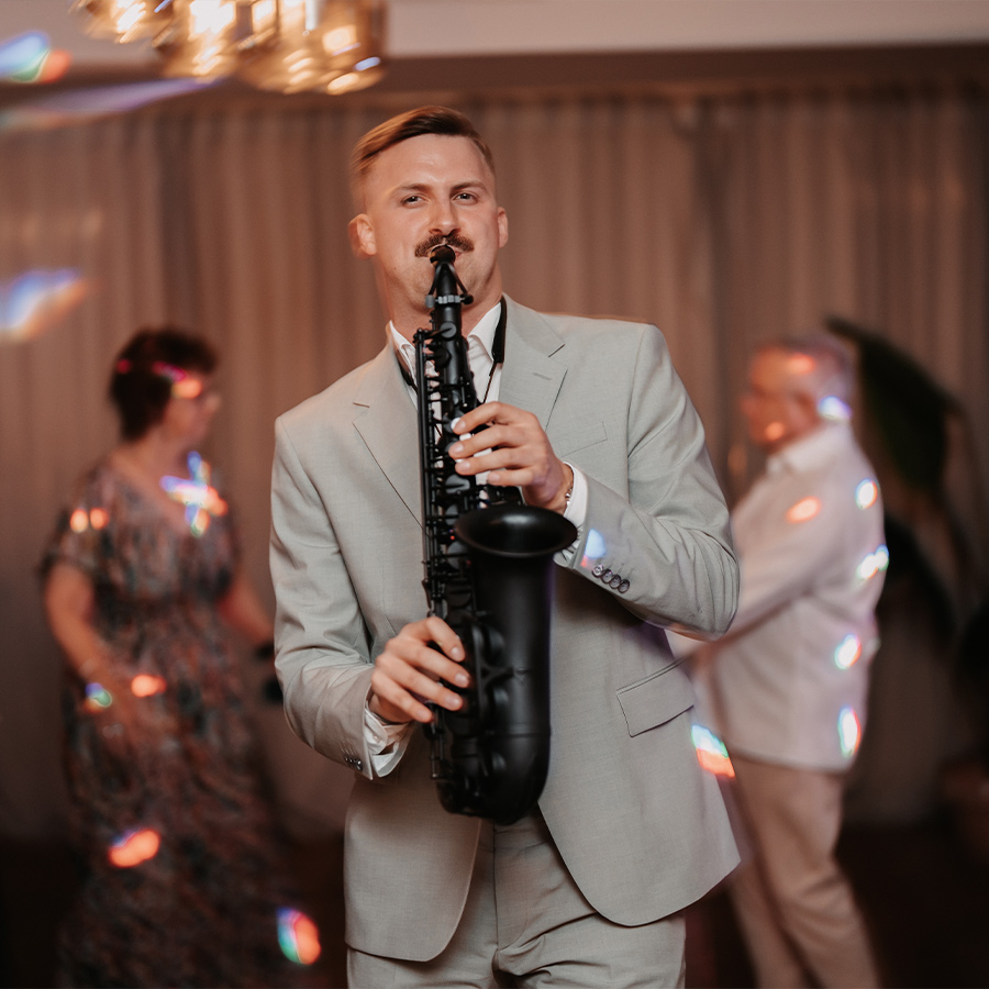 Marius Trapp spielt Saxophon zwischen den Gästen einer Abendveranstaltung